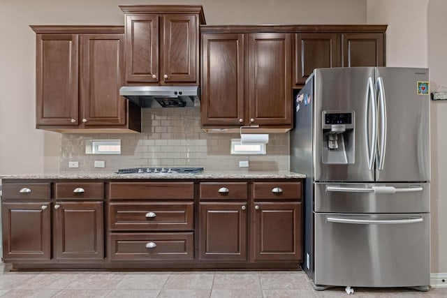 614 Spanish Mustang Dr, Cedar Park, TX 78613 - kitchen with appliances with stainless steel finishes, under cabinet range hood, decorative backsplash, light stone countertops, and dark brown cabinets