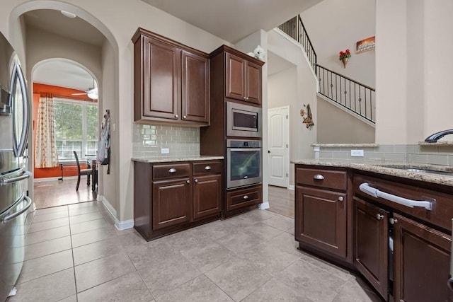 614 Spanish Mustang Dr, Cedar Park, TX 78613 - kitchen with stainless steel appliances, decorative backsplash, light stone countertops, and dark brown cabinets