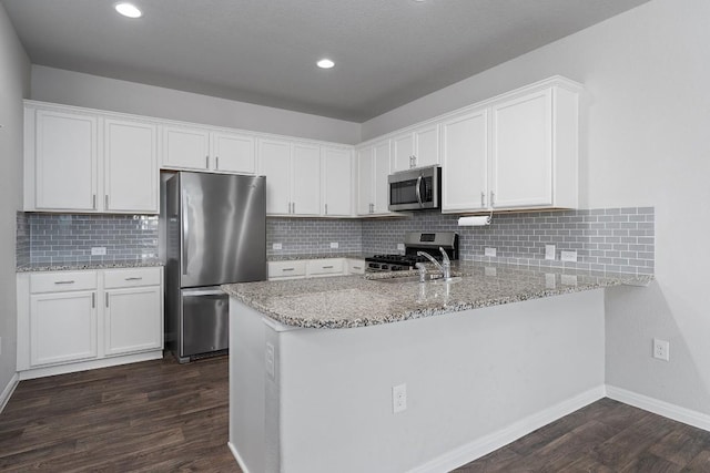 14405 Frankel Loop Unit 34A, Pflugerville, TX 78660 - kitchen with stainless steel appliances, dark wood-style flooring, light stone countertops, white cabinetry, and a peninsula