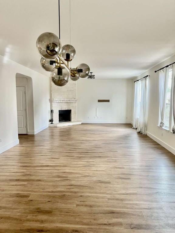 2118 Howell Mountain Dr, Cedar Park, TX 78613 - unfurnished living room with a chandelier, wood finished floors, arched walkways, and a large fireplace