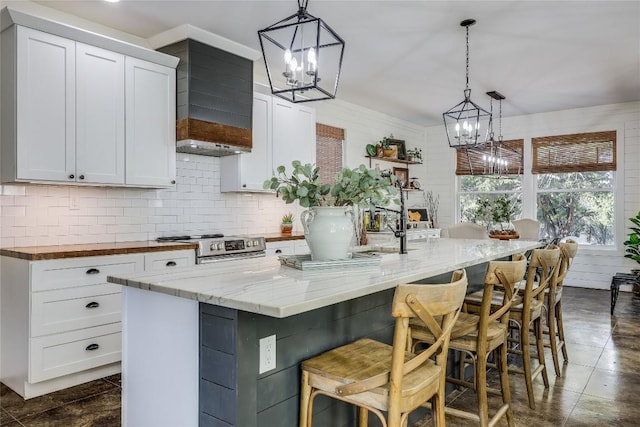 20008 Victoria Chase Rd, Lago Vista, TX 78645 - kitchen featuring a chandelier, an island with sink, white cabinetry, tasteful backsplash, and stainless steel range oven
