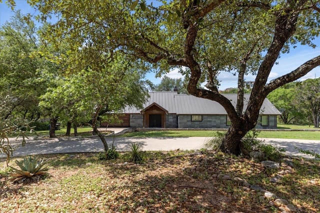2817 Tradewind Dr, Spicewood, TX 78669 - view of front of house featuring curved driveway, a metal roof, stone siding, and an attached garage