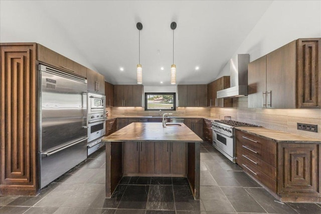 2817 Tradewind Dr, Spicewood, TX 78669 - kitchen with built in appliances, wall chimney range hood, butcher block counters, lofted ceiling, and backsplash