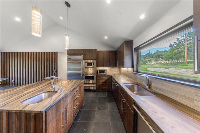 2817 Tradewind Dr, Spicewood, TX 78669 - kitchen with built in appliances, vaulted ceiling, dark tile patterned flooring, backsplash, and hanging light fixtures