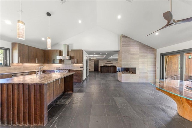 2817 Tradewind Dr, Spicewood, TX 78669 - kitchen featuring wall chimney exhaust hood, high vaulted ceiling, open floor plan, modern cabinets, and an island with sink