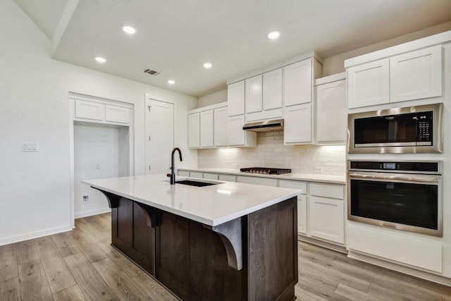 564 Biscayne Bay Bnd, Kyle, TX 78640 - kitchen featuring stainless steel appliances, backsplash, white cabinetry, a center island with sink, and recessed lighting