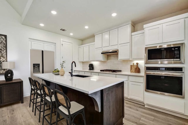 564 Biscayne Bay Bnd, Kyle, TX 78640 - kitchen featuring stainless steel appliances, a center island with sink, a kitchen bar, tasteful backsplash, and light countertops