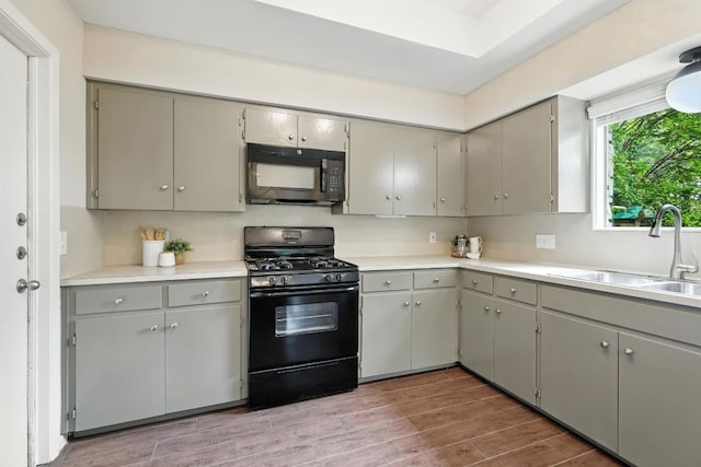 11915 River Oaks Trl, Austin, TX 78753 - kitchen with black appliances, gray cabinets, wood finished floors, and light countertops