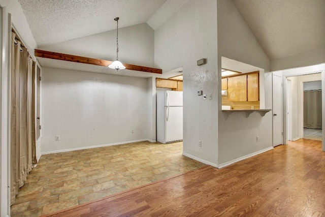 1000 Milford Way, Austin, TX 78745 - kitchen featuring freestanding refrigerator, a textured ceiling, a breakfast bar, high vaulted ceiling, and decorative light fixtures