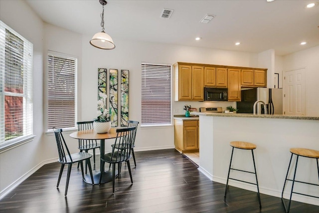 2211 Wilson St, Austin, TX 78704 - kitchen with black microwave, stainless steel fridge with ice dispenser, healthy amount of natural light, a kitchen bar, and recessed lighting