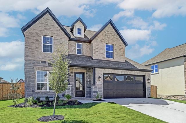 17309 Howdy Way, Manor, TX 78653 - view of front of house with concrete driveway, stone siding, and a garage