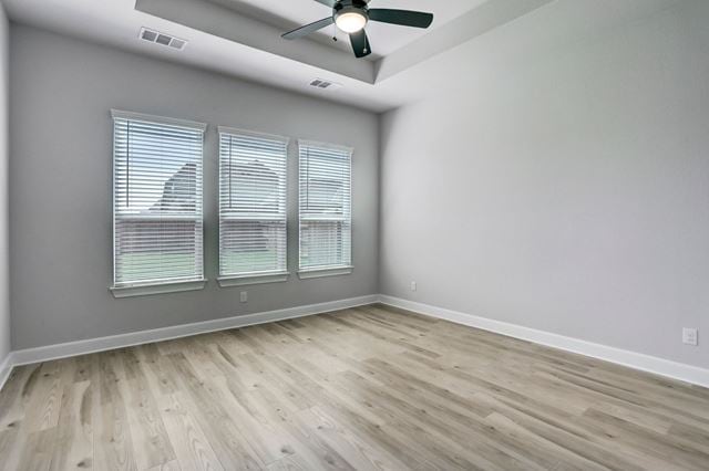 17309 Howdy Way, Manor, TX 78653 - empty room featuring a tray ceiling, a ceiling fan, and wood finished floors