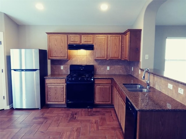 3304 Wickham Ln, Austin, TX 78725 - kitchen with black appliances, under cabinet range hood, dark stone countertops, a peninsula, and backsplash