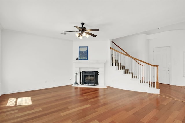 2310 Dervingham Dr, Cedar Park, TX 78613 - unfurnished living room featuring a fireplace with flush hearth, wood finished floors, ceiling fan, and stairs