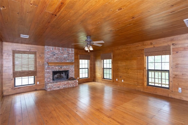 2874 Fm 1704, Elgin, TX 78621 - unfurnished living room with wooden ceiling, hardwood / wood-style floors, wood walls, ceiling fan, and a fireplace
