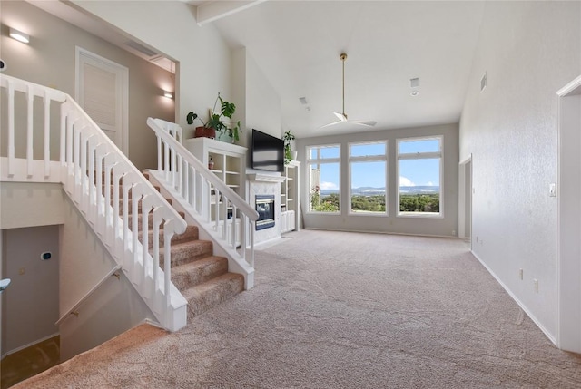4705 Comanche, Lago Vista, TX 78645 - unfurnished living room with high vaulted ceiling, carpet floors, a high end fireplace, stairway, and ceiling fan