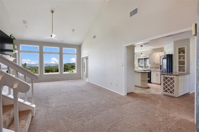 4705 Comanche, Lago Vista, TX 78645 - unfurnished living room with high vaulted ceiling, light carpet, plenty of natural light, and stairway