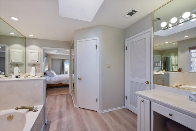 4705 Comanche, Lago Vista, TX 78645 - ensuite bathroom featuring wood finished floors, a bath, vanity, a skylight, and recessed lighting