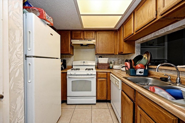 7825 Beauregard Cir Unit 25, Austin, TX 78745 - kitchen with white appliances, under cabinet range hood, brown cabinets, and light tile patterned floors