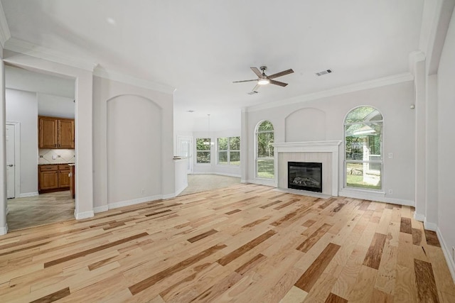 501 Flamingo Blvd, Lakeway, TX 78734 - unfurnished living room featuring light wood finished floors, a ceiling fan, crown molding, and a tiled fireplace