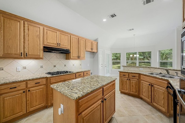 501 Flamingo Blvd, Lakeway, TX 78734 - kitchen with under cabinet range hood, decorative backsplash, gas cooktop, light stone countertops, and vaulted ceiling