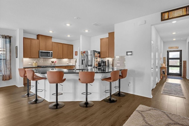 4909 Teverola Dr, Round Rock, TX 78665 - kitchen with stainless steel appliances, dark wood finished floors, a peninsula, dark countertops, and backsplash