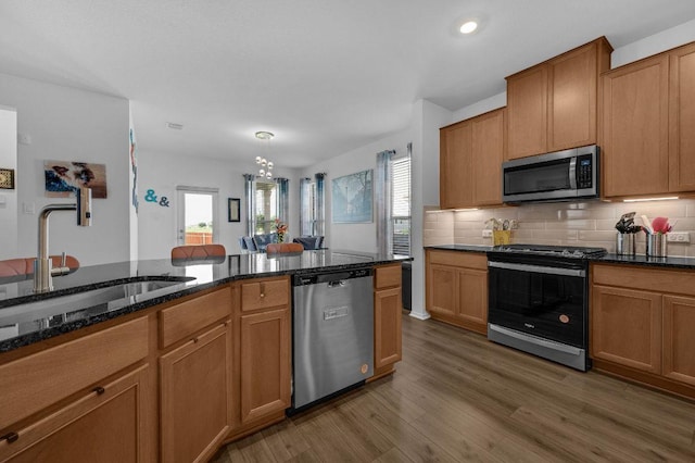 4909 Teverola Dr, Round Rock, TX 78665 - kitchen with stainless steel appliances, plenty of natural light, dark stone countertops, wood finished floors, and recessed lighting