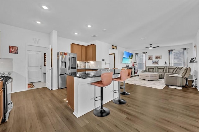 4909 Teverola Dr, Round Rock, TX 78665 - kitchen with stainless steel fridge with ice dispenser, a breakfast bar area, electric stove, wood finished floors, and open floor plan