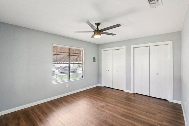 755 E Bellville St, Giddings, TX 78942 - unfurnished bedroom featuring multiple closets, dark wood finished floors, and ceiling fan