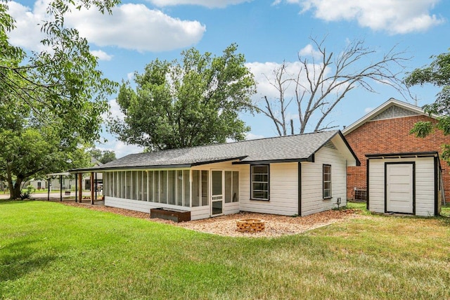 755 E Bellville St, Giddings, TX 78942 - rear view of house with a sunroom, a yard, a shingled roof, a fire pit, and a storage unit