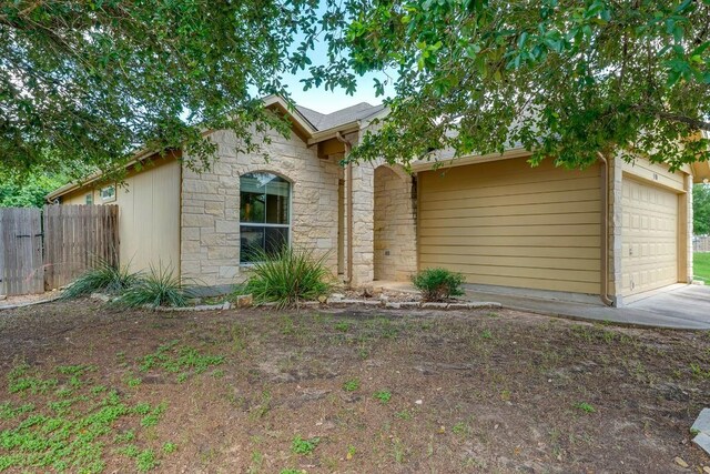 15300 Lucian St, Austin, TX 78725 - view of front facade featuring stone siding, a garage, and driveway