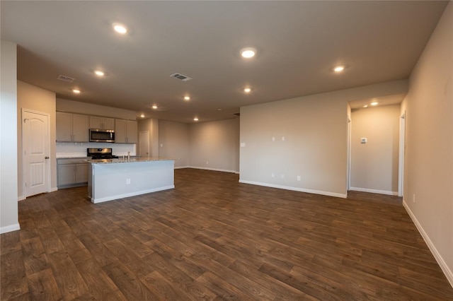 124 Ballyneal Ln, San Marcos, TX 78666 - kitchen featuring appliances with stainless steel finishes, dark wood-style flooring, a center island with sink, open floor plan, and recessed lighting