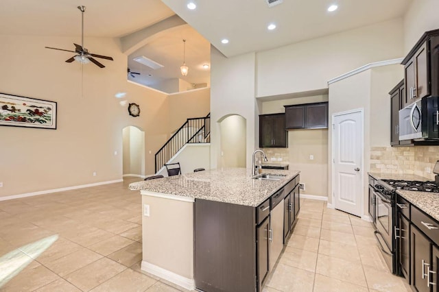 16225 Chianti Cv, Pflugerville, TX 78660 - kitchen featuring gas stove, stainless steel microwave, arched walkways, light tile patterned floors, and high vaulted ceiling