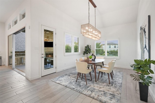 405 Maialina Cv, Lakeway, TX 78738 - dining room with a chandelier, wood finished floors, high vaulted ceiling, and a lit fireplace