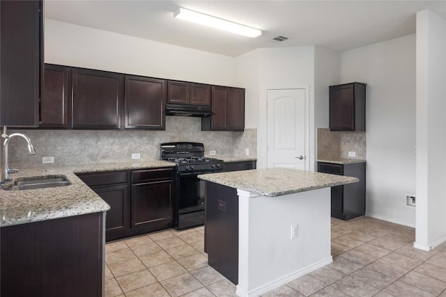10205 Gertrudis Loop, Austin, TX 78747 - kitchen with black gas stove, under cabinet range hood, backsplash, light tile patterned floors, and light stone countertops
