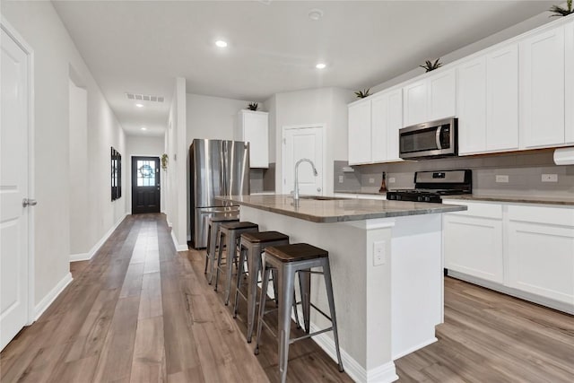202 Grapefruit Rd, Hutto, TX 78634 - kitchen featuring stainless steel appliances, light wood-type flooring, a kitchen island with sink, a breakfast bar area, and recessed lighting