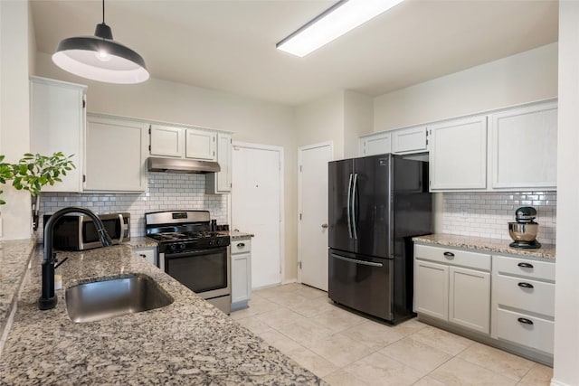 903 Thackeray Ln, Pflugerville, TX 78660 - kitchen featuring stainless steel appliances, under cabinet range hood, decorative backsplash, light stone counters, and hanging light fixtures