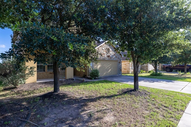 3604 Rosalina Loop, Round Rock, TX 78665 - view of property hidden behind natural elements featuring stone siding, concrete driveway, a front lawn, and a garage