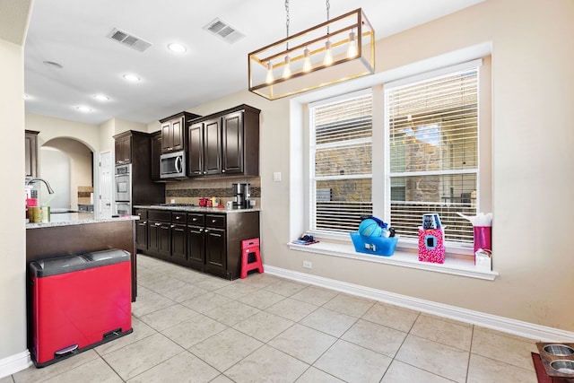 3604 Rosalina Loop, Round Rock, TX 78665 - kitchen featuring stainless steel appliances, arched walkways, light tile patterned floors, pendant lighting, and backsplash