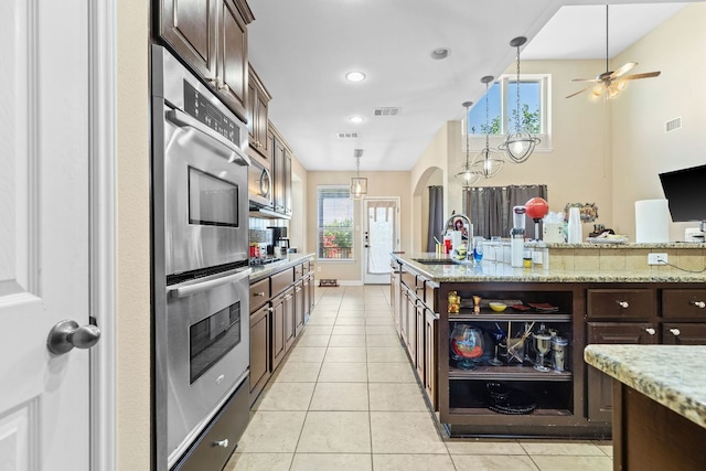 3604 Rosalina Loop, Round Rock, TX 78665 - kitchen with stainless steel double oven, light tile patterned floors, dark brown cabinets, pendant lighting, and healthy amount of natural light