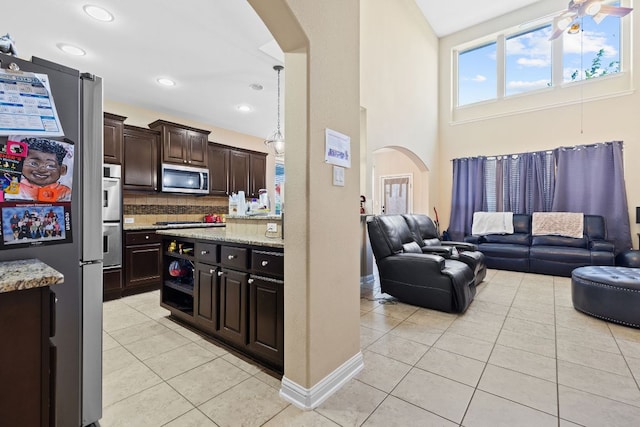 3604 Rosalina Loop, Round Rock, TX 78665 - kitchen with arched walkways, stainless steel appliances, light tile patterned floors, open floor plan, and recessed lighting