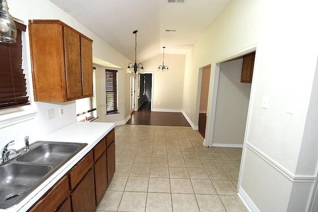 213 Bronc Dr, Copperas Cove, TX 76522 - kitchen with vaulted ceiling, light tile patterned floors, light countertops, decorative light fixtures, and brown cabinetry