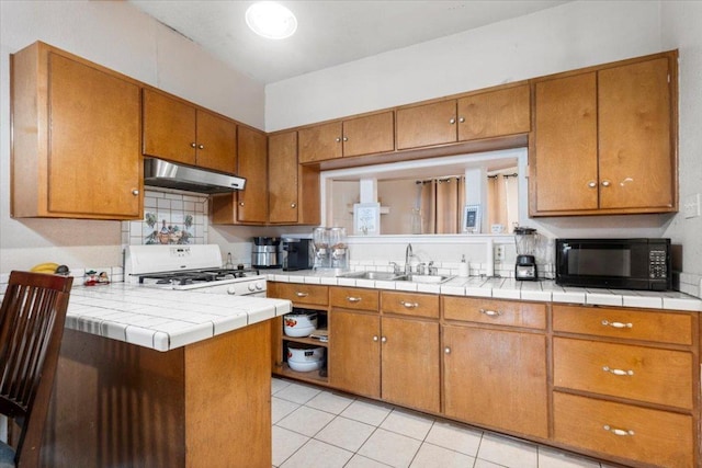 909 W 3rd St, Taylor, TX 76574 - kitchen featuring black microwave, extractor fan, brown cabinets, range, and backsplash