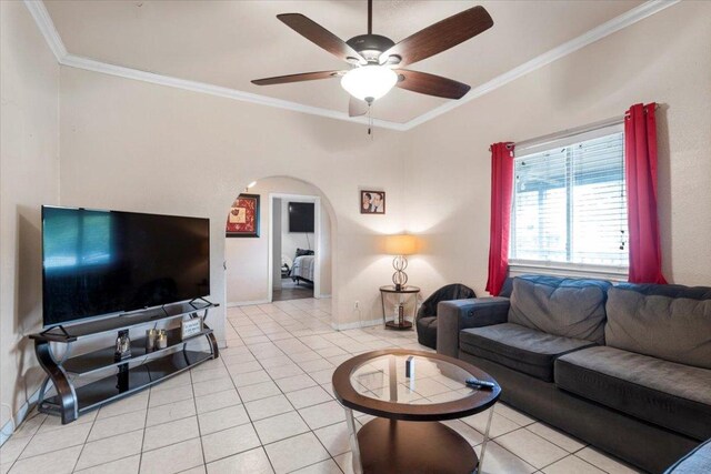 909 W 3rd St, Taylor, TX 76574 - living room featuring crown molding, light tile patterned floors, a ceiling fan, and arched walkways