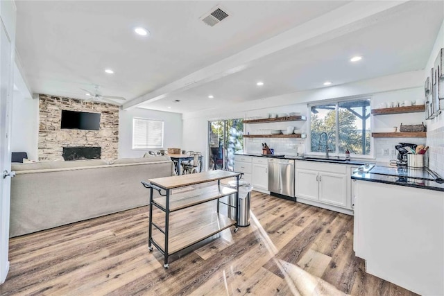10902 Beach Rd, Leander, TX 78641 - kitchen featuring open shelves, a fireplace, dark countertops, stainless steel dishwasher, and light wood-type flooring