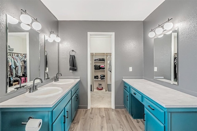 255 Mesquite Dr, Cedar Creek, TX 78612 - bathroom featuring a walk in closet, wood finished floors, double vanity, and a textured wall