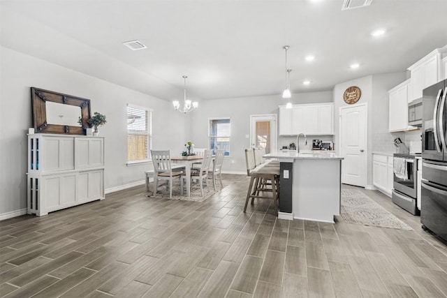 5867 Copano Loop, Belton, TX 76513 - kitchen featuring stainless steel appliances, wood finished floors, a chandelier, a center island with sink, and recessed lighting