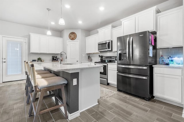 5867 Copano Loop, Belton, TX 76513 - kitchen featuring appliances with stainless steel finishes, decorative backsplash, a kitchen breakfast bar, a kitchen island with sink, and white cabinets