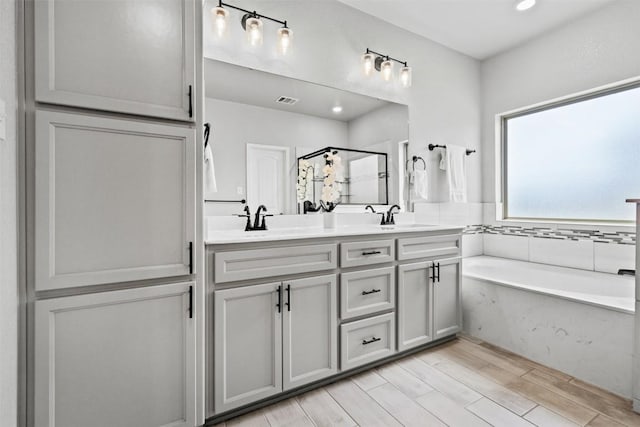 7516 Hardin Dr, Temple, TX 76502 - full bathroom featuring a bath, a stall shower, double vanity, wood finished floors, and recessed lighting