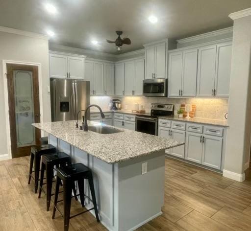 7516 Hardin Dr, Temple, TX 76502 - kitchen featuring appliances with stainless steel finishes, crown molding, tasteful backsplash, an island with sink, and a breakfast bar area